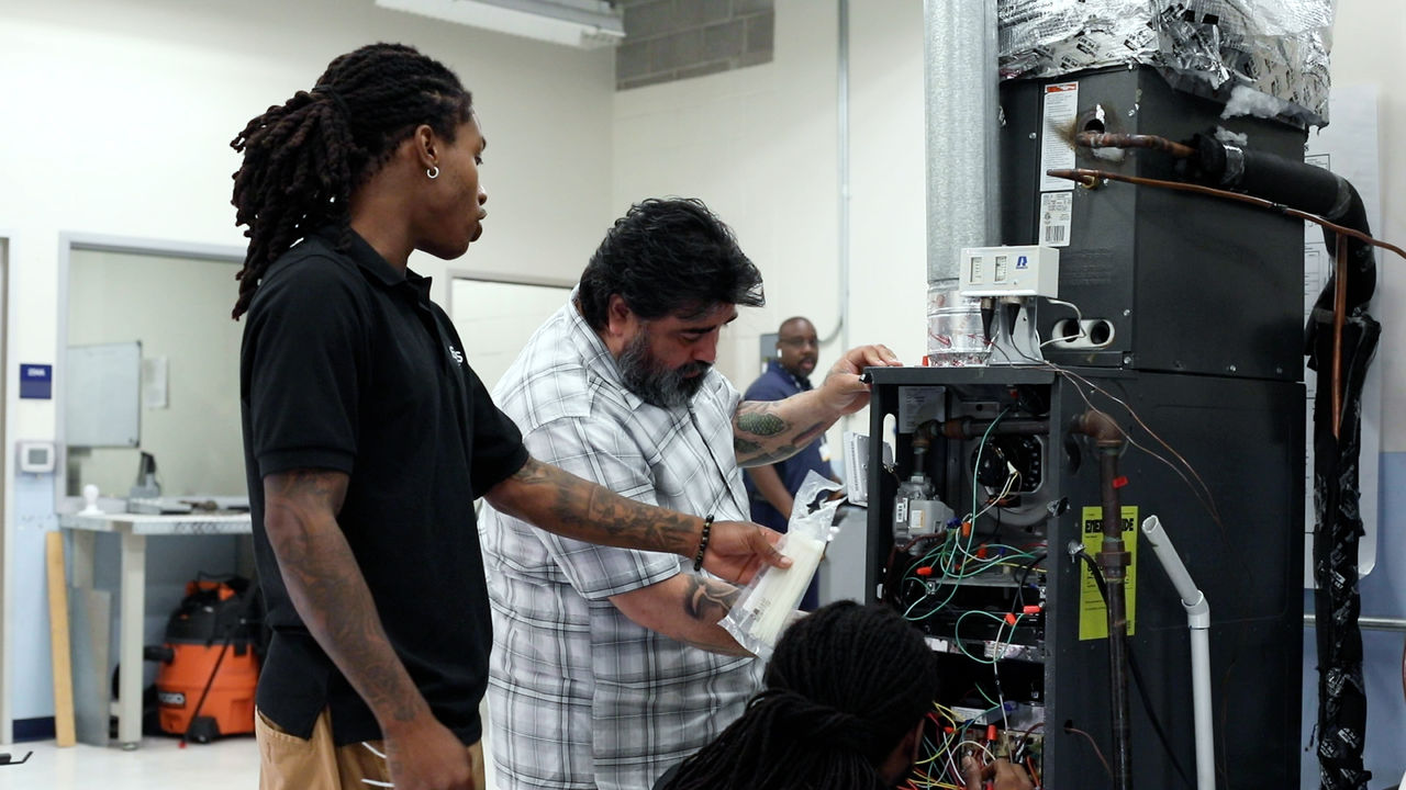 Technicians repairing HVAC unit in workshop setting
